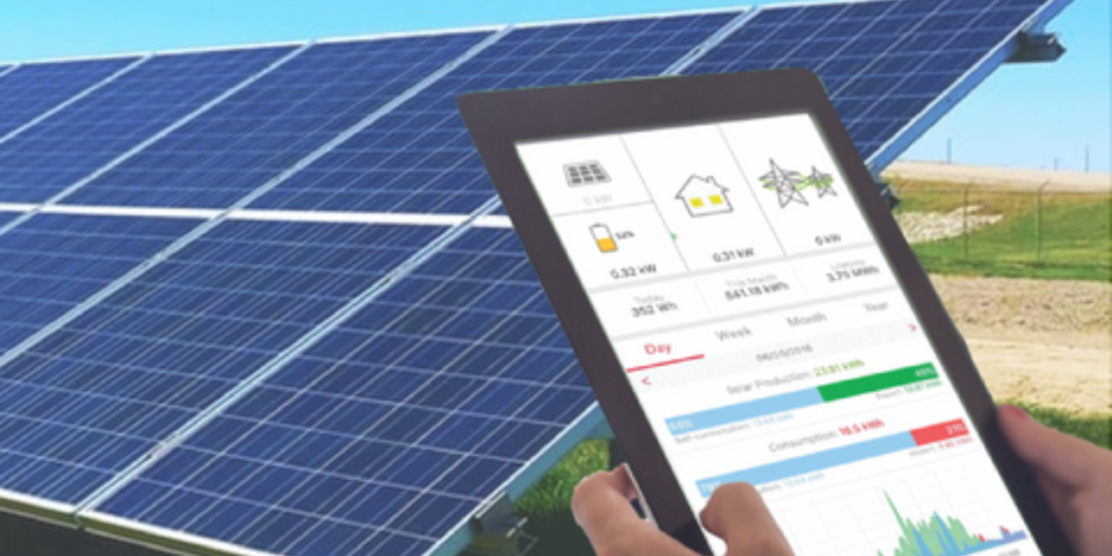 tablet in hand showing solar monitoring with background of solar plates.